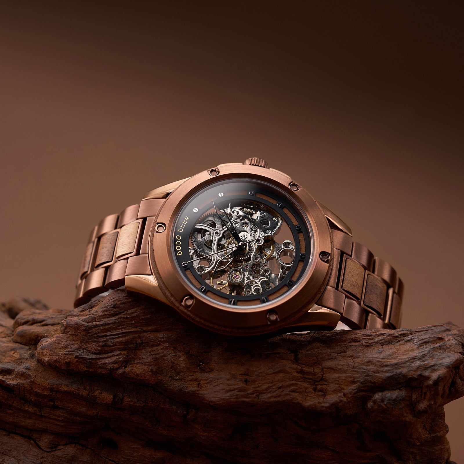 Bronze wristwatch with visible mechanical components on a wooden surface