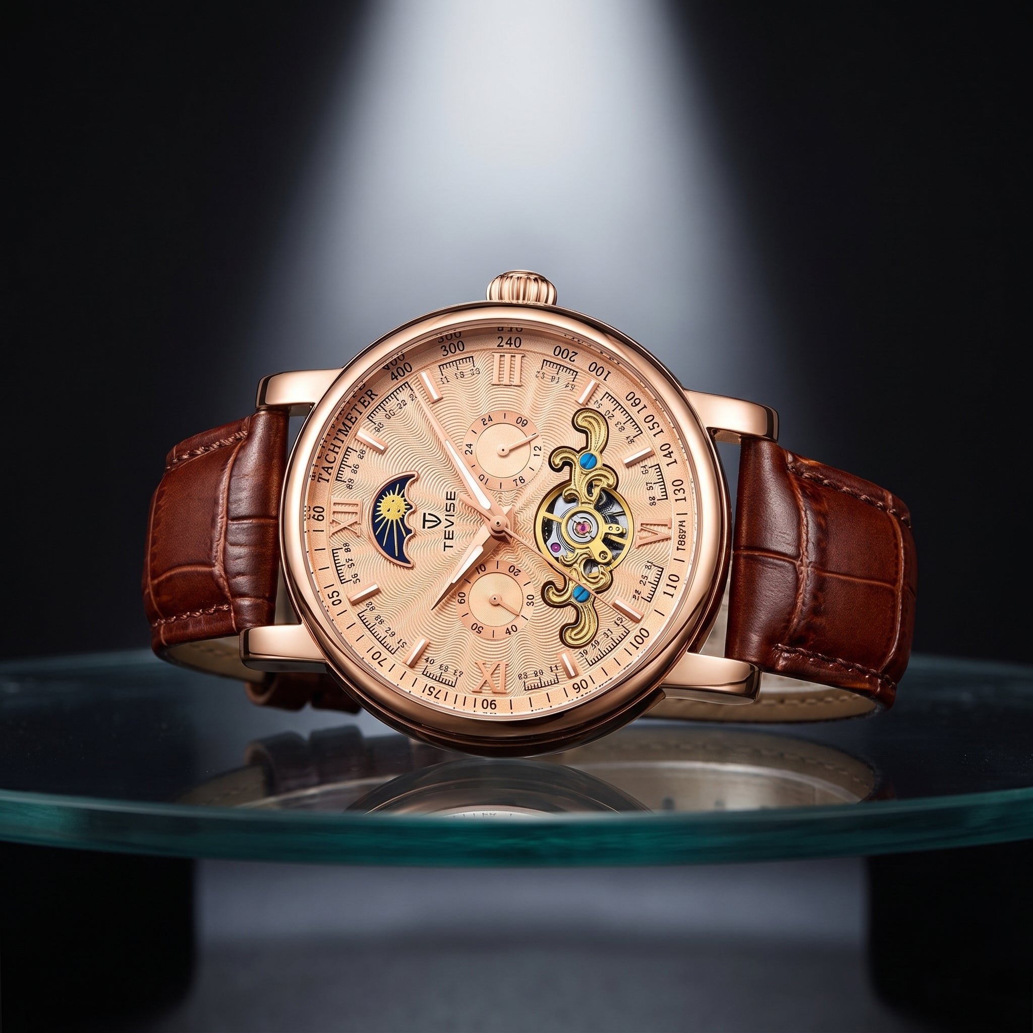 A luxury mechanical watch with a rose gold-toned case, a brown leather strap, and a detailed skeleton dial showing ornate gold and blue movement details, displayed on a glass surface against a dark background.