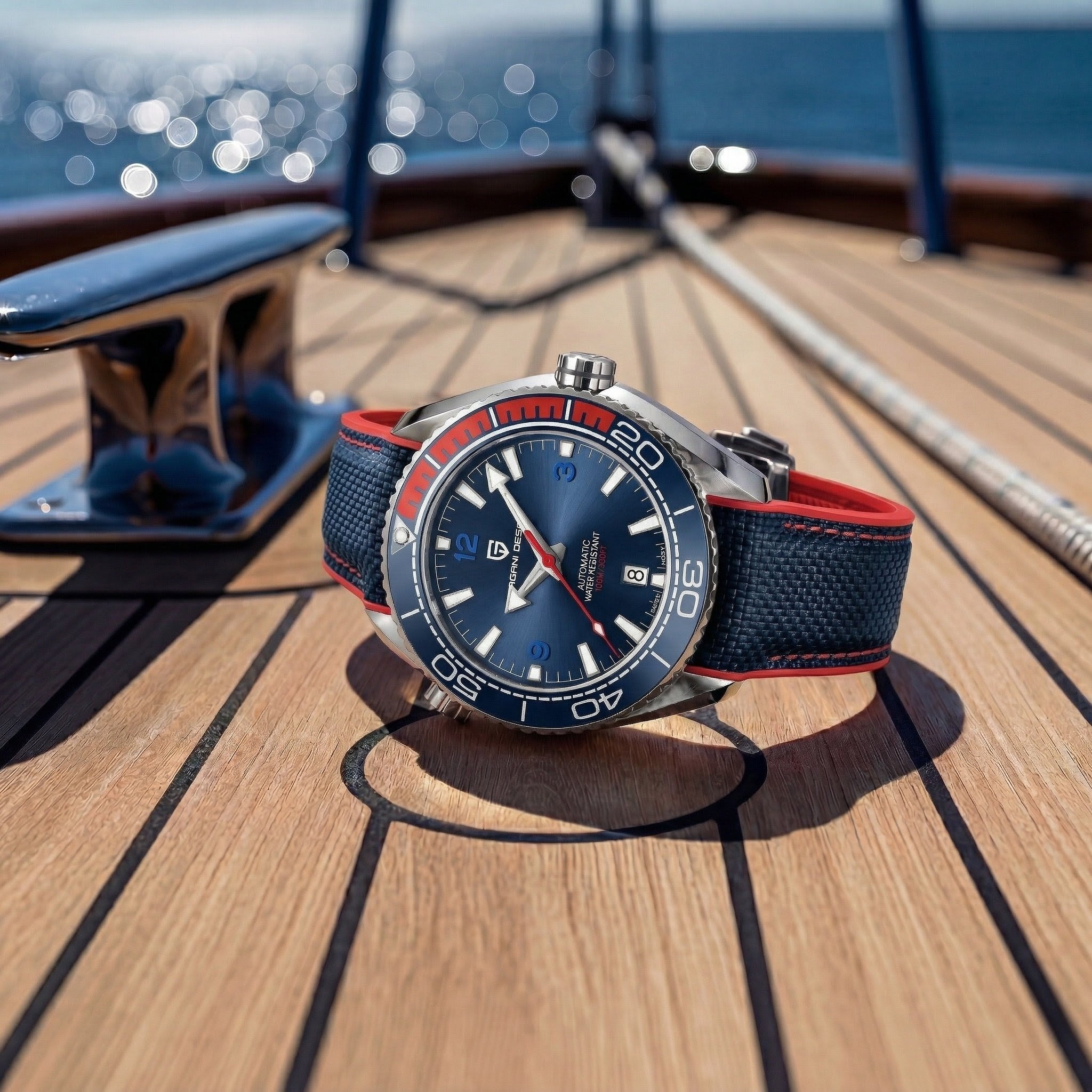 Watch with blue face and red strap on a wooden deck with ocean view