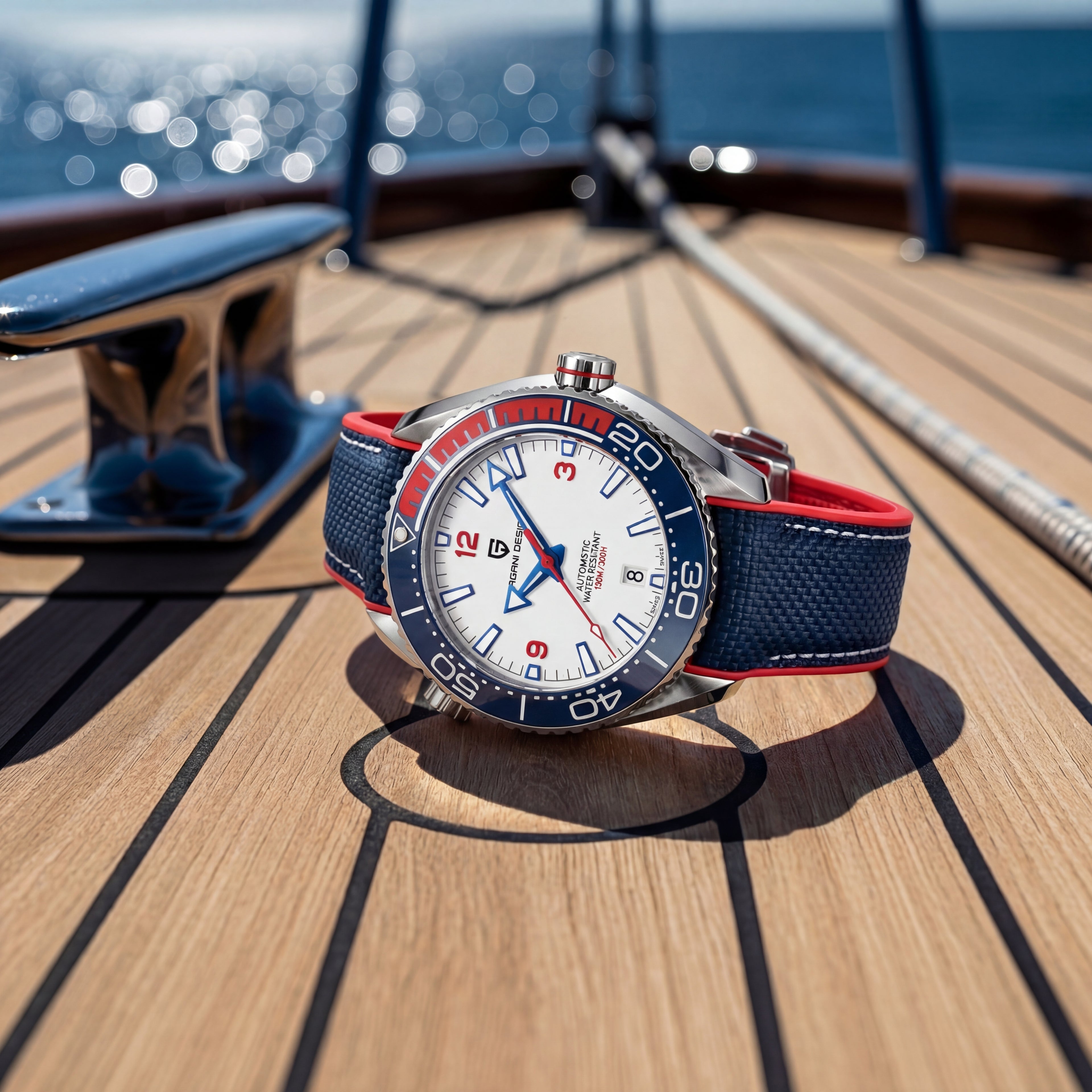 Watch with a blue and red strap on a wooden deck with ocean view