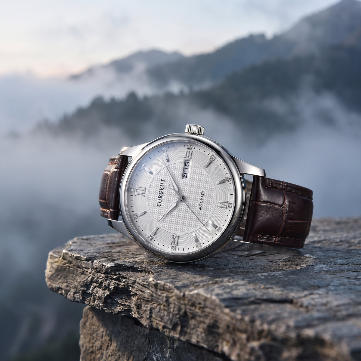 A wristwatch with a silver-toned round case, white dial, and dark brown leather strap, resting on a rough stone ledge with misty mountains in the background.