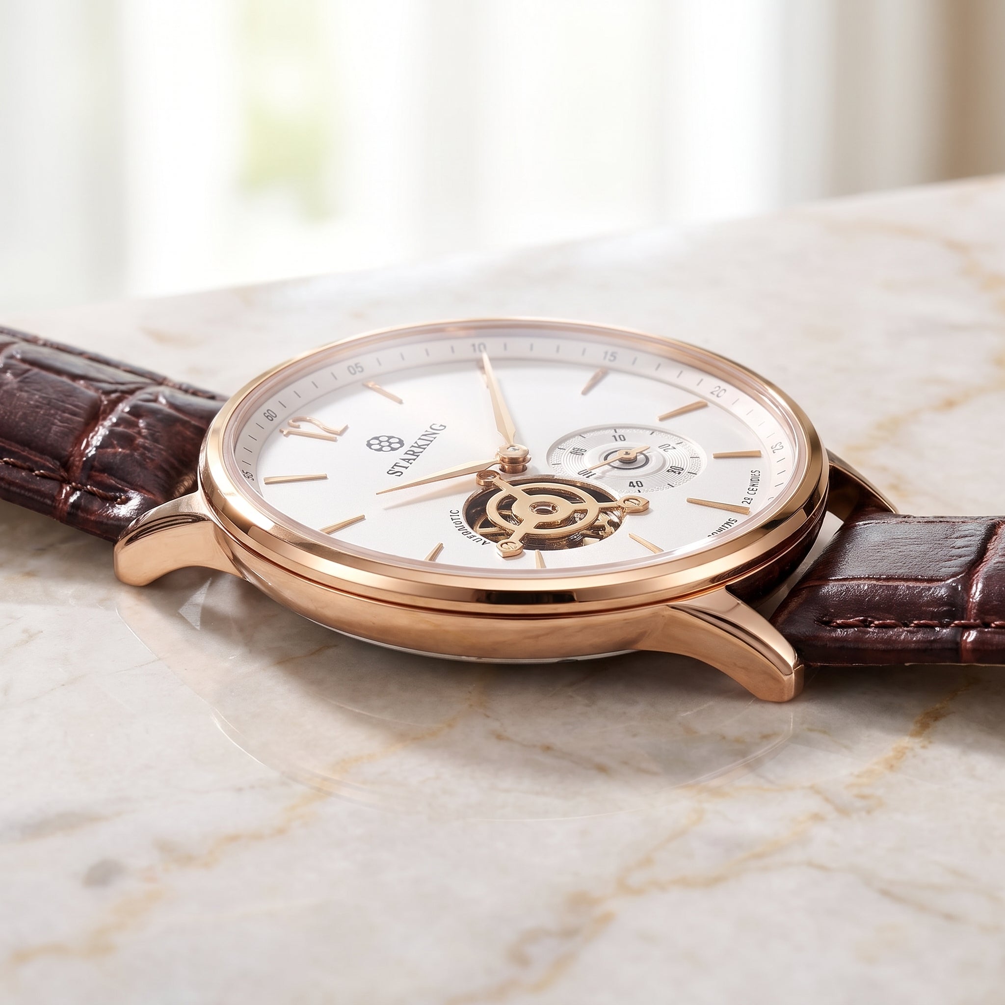 A luxury wristwatch with a rose gold case, white dial, and brown alligator leather strap, resting on a light marble surface.